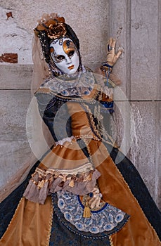 Woman poses in ornate, detailed costume, mask and hat, at the Doges Palace, St Mark`s Square during during Venice Carnival, Italy