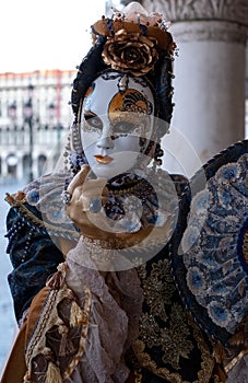 Woman poses in ornate, detailed costume, mask and hat, at the Doges Palace, St Mark`s Square during during Venice Carnival, Italy
