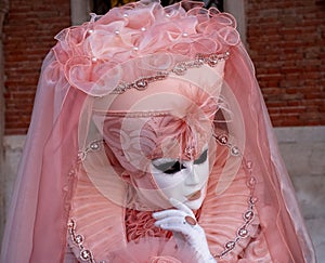 Woman poses in ornate, detailed costume, mask and hat, at the Doges Palace, St Mark`s Square during during Venice Carnival, Italy