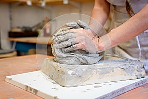 Close up of woman potter hands works with clay and ceramic, craftsman hands. knead and moistens the clay before work in ceramic