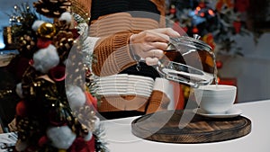 Close up of woman pouring cup of tea from kettle at home