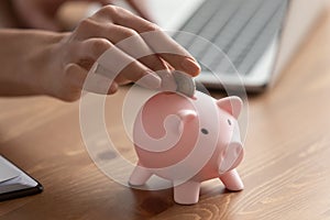 Close up of woman put coin into piggybank