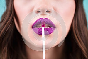 Close up woman puts lipstick, lip gloss on her lips. Bright purple lipstick color. Skin Care Cosmetics