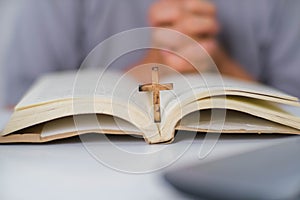 Close-up of a woman reading an open bible, praying and holding hands on her bible. Spiritual or bible study concept