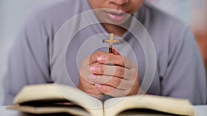 Close-up of a woman reading an open bible, praying and holding hands on her bible. Spiritual or bible study concept.