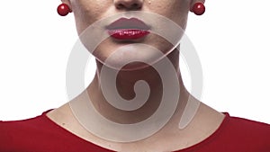 Close up of a woman with red lipstick and earrings licking her lips