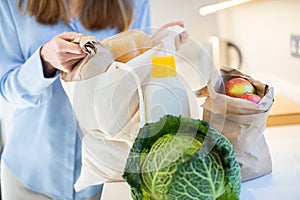 Close Up Of Woman Returning Home From Shopping Trip Unpacking Groceries In Plastic Free Packaging photo