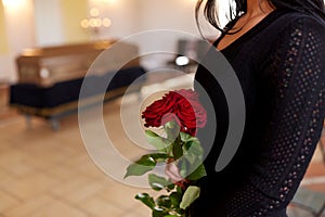 Close up of woman with roses and coffin at funeral