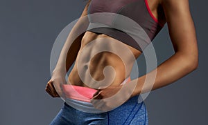 Close up of woman`s abs with tanned skin on gray background