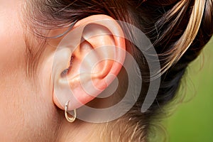 Close up of woman\'s ear with hearing aid in earring.