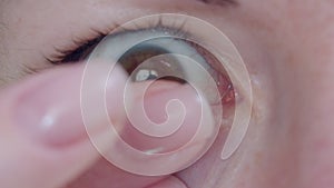 Close-up of a woman's eye putting on a contact lens