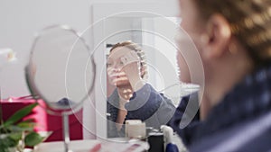 close-up of a woman's face. woman doing makeup while sitting in front of a mirror at home