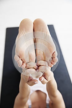 Close-up of a woman`s feet stretching by catching both toes with her fingers