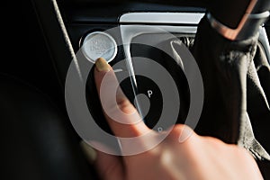 Close up of woman`s finger pressing the start/stop engine button on car