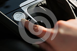 Close up of woman`s finger pressing the start/stop engine button on car