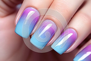Close up of woman\'s fingernails with pastel blue, pink and purple ombre colored nail polish design
