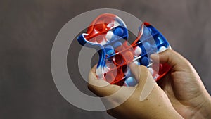 Close-up of a woman`s fingers playing with a simple dimple silicone toy in the shape of a duck. Modern children`s anti-stress toy