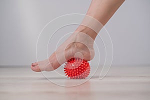 Close-up of a woman& x27;s foot on a massage ball with spikes.