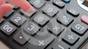Close-up of a woman\'s hand counting household expenses on a calculator related to monthly bank payments