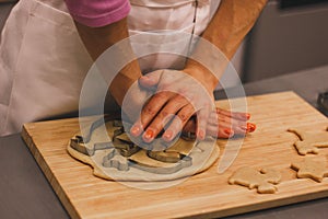 Close-up of a woman`s hand with a dough. The woman is cutting a cookie with a cookie cutter in the shape of a little.