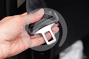 Close up of a woman`s hand fastening seat belt while sitting inside a car for safety before riding on the road