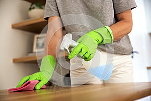 Close-up of woman\'s hand in gloves is wiping the table with cleaning liquid