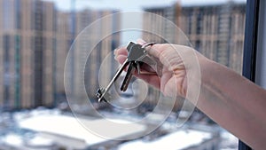 Close-up of a woman's hand holding a bunch of keys to a new apartment against the background of multi-storey