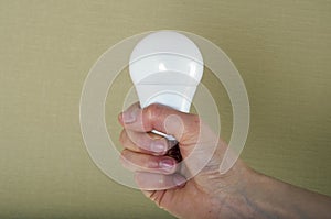 Close up of woman`s hand holding light bulb. Green background