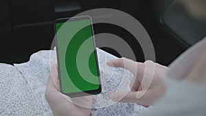 Close up of a woman`s hand holding a mobile telephone with green screen in car chroma key smartphone technology