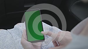 Close up of a woman`s hand holding a mobile telephone with green screen in car chroma key smartphone technology