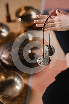 Close-up of a woman's hand holding Tibetan bells for sound therapy. Tibetan cymbals