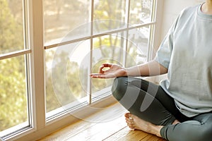 Close-up of woman`s hand during meditation sitting on windowsill. Mental healthcare concept