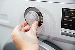 Close-up of a woman& x27;s hand on the mode switch of the washing machine.