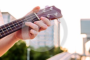 Close-up of woman`s hand on the neck of a ukulele
