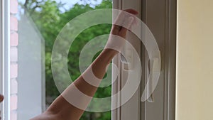 Close-up of a woman`s hand opens a plastic white window to ventilate the room