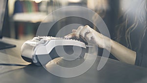 Close up of woman s hand paying with a credit card in a store. Enter the PIN code.