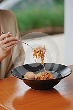 close up woman's hand is picking up spaghetti with a fork