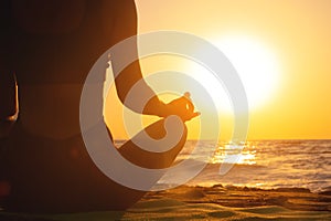 Close-up woman's hand practicing yoga silhouette, meditation in lotus position on the beach, feel so comfortable and