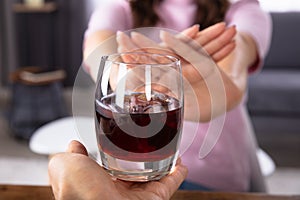 Woman Refusing Glass Of Drink Offered By Person