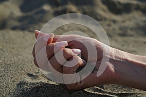 Close-up of a woman& x27;s hand releasing falling sand.