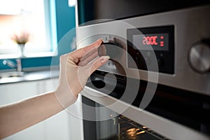 Close up of woman's hand setting temperature control on oven photo