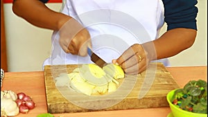 Close up of woman`s hand slicing onion on a wooden board