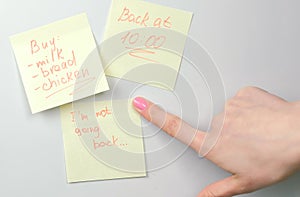 Close up woman`s hand sticks yellow sticker papers notes on a white board. Family notes.