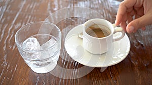 Close-up of woman`s hand stirring an espresso and pouring it into a glass with ice