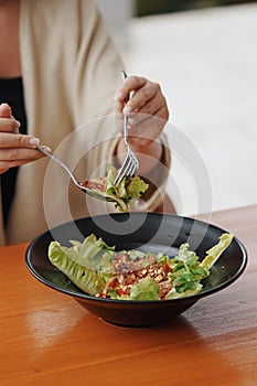 close up woman's hand is taking salad from plate