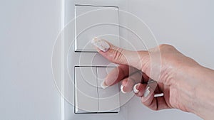 Close-up woman's hand turns off the white wall light switch, copy space, space for text.Concept of energy saving electricity