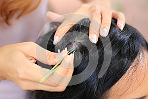 Close up Woman`s hand using tweezers to plucking gray hair roots from head