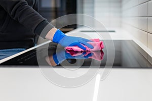 Close-up woman`s hand wipes the electric stove with rag. Housekeeping cleaning concept.