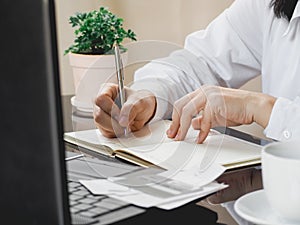 Close up of woman`s hand writing on a paper blank notebook on the table. business concept. work at home