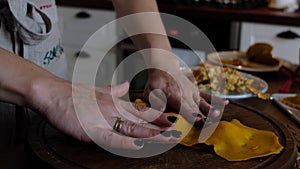 Close-up woman's hands cover the dough for pumpkin and pastry ravioli. homemade ravioli, dumplings. cover the rolled